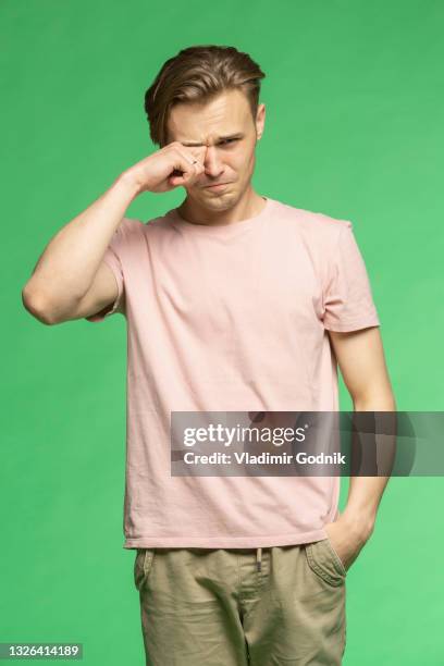 studio portrait unhappy young man crying - rubbing eyes stock pictures, royalty-free photos & images