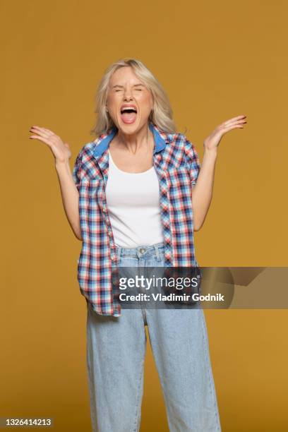 studio portrait angry woman screaming on yellow background - ongeduldig stockfoto's en -beelden