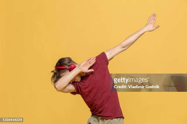 carefree young man with headphones listening to music and dabbing - dab dance stock pictures, royalty-free photos & images