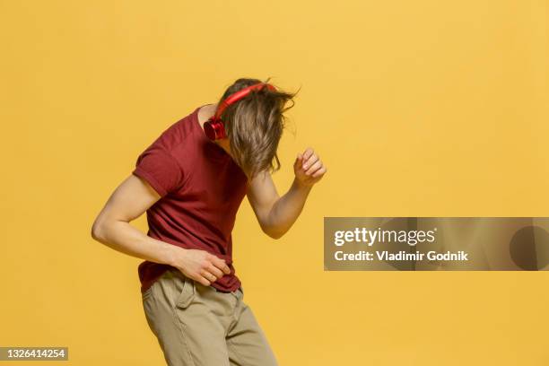 studio portrait young man with headphones dancing on yellow background - nur junge männer stock-fotos und bilder