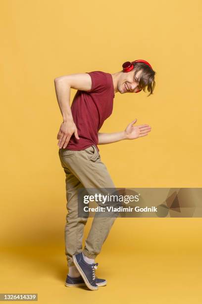 portrait playful young man with headphones dancing - junger mann ganzkörper stock-fotos und bilder