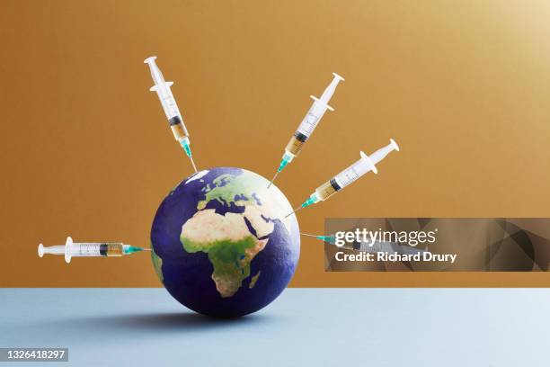 a world globe being vaccinated - idea studio shot stockfoto's en -beelden