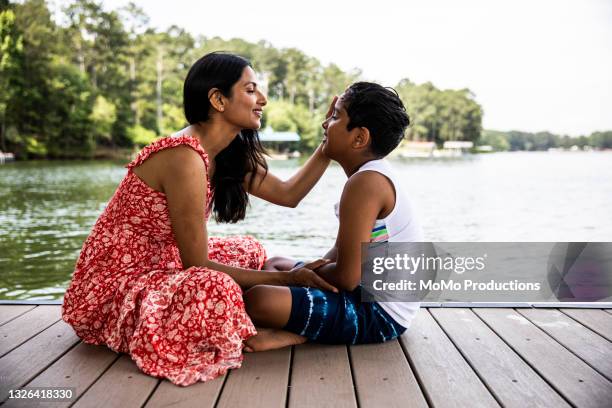 mother and son embracing on dock at lake - day in the life series stock-fotos und bilder