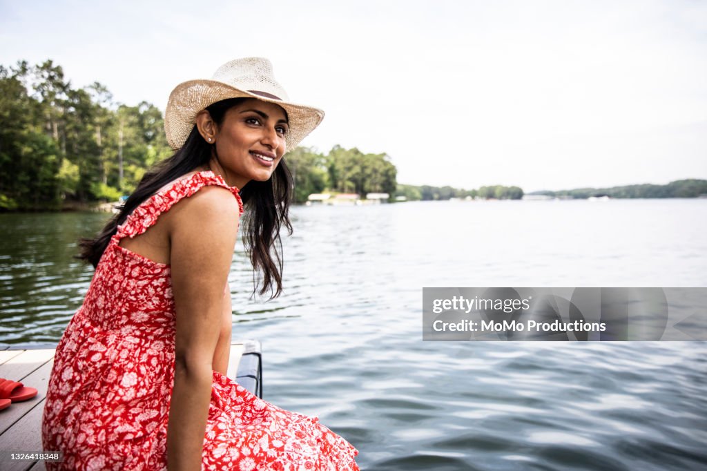 Portrait of beautiful woman sitting on dock at lake