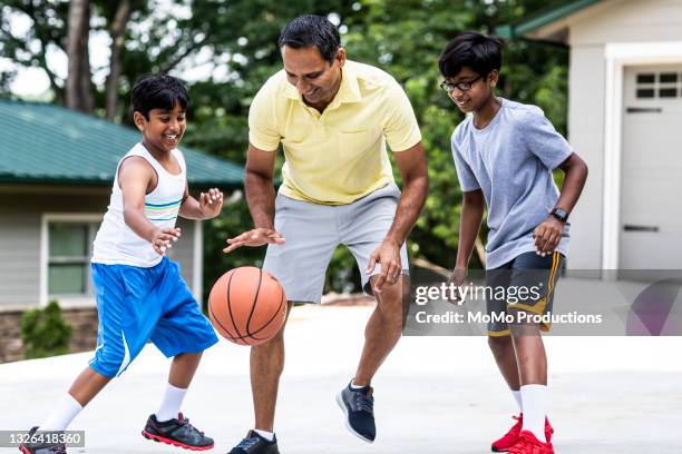 father and sons playing basketball in driveway - teen boy shorts stock pictures, royalty-free photos & images
