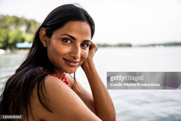 portrait of beautiful woman sitting on dock at lake - brown eye stock pictures, royalty-free photos & images