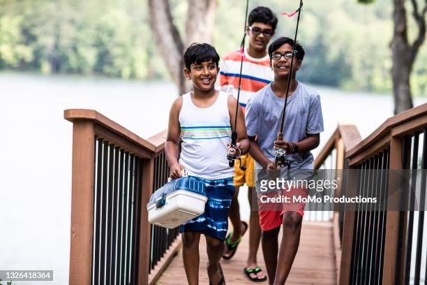 young boys carrying fishing equipment at lake - rural indian family stock pictures, royalty-free photos & images