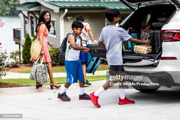 family unloading luggage at vacation rental lakehouse - indian subcontinent ethnicity stock pictures, royalty-free photos & images