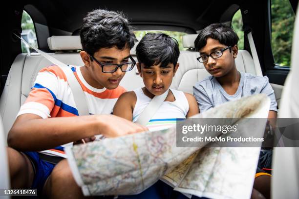 boys looking at map in back of car - indian family vacation stock pictures, royalty-free photos & images