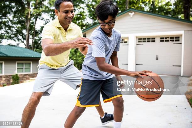 father and son playing basketball in driveway - match action stock pictures, royalty-free photos & images