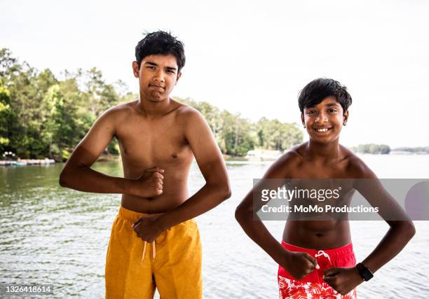 boys making muscles at lake - teen boy shorts stock-fotos und bilder