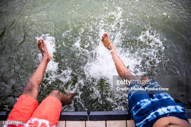 young boys splashing water at lake - child and unusual angle stock-fotos und bilder