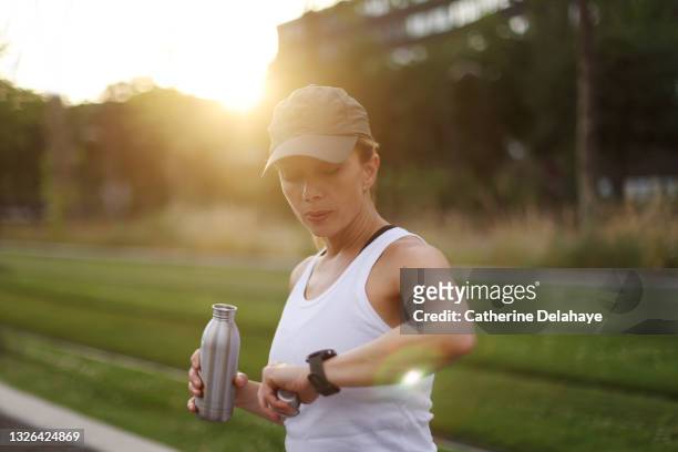 a woman looking at her watch during her sports training - water canteen stock pictures, royalty-free photos & images