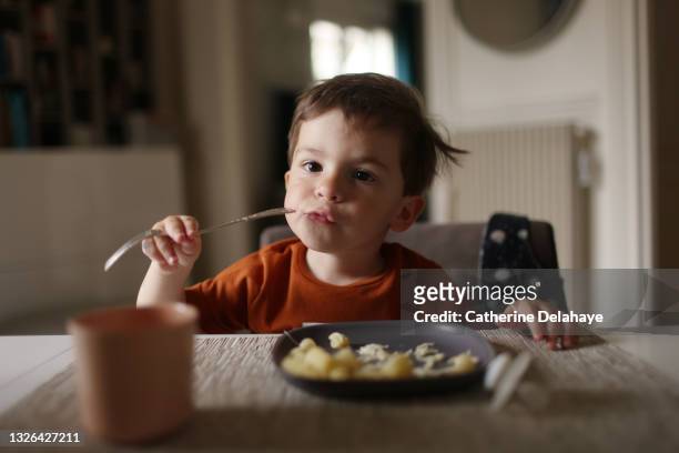 a 3 year old little boy having his lunch at home - eat stockfoto's en -beelden