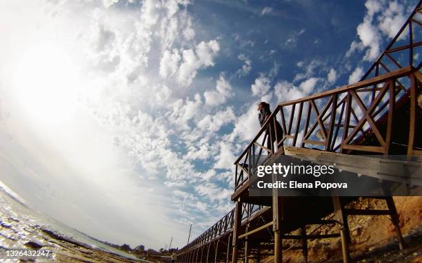 young adult woman standing at the bridge against cloudy sky background - larnaca stock pictures, royalty-free photos & images