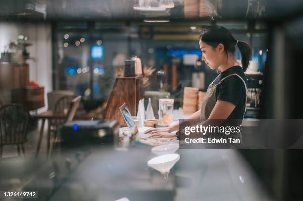 asian chinese female barista using laptop while enjoying dinner at coffee shop bar counter - bijbaantje stockfoto's en -beelden
