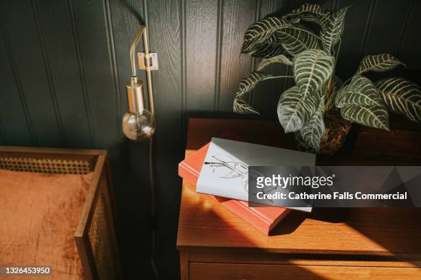 reading glasses on two books stacked on a bedside table - reading glasses on table stock pictures, royalty-free photos & images
