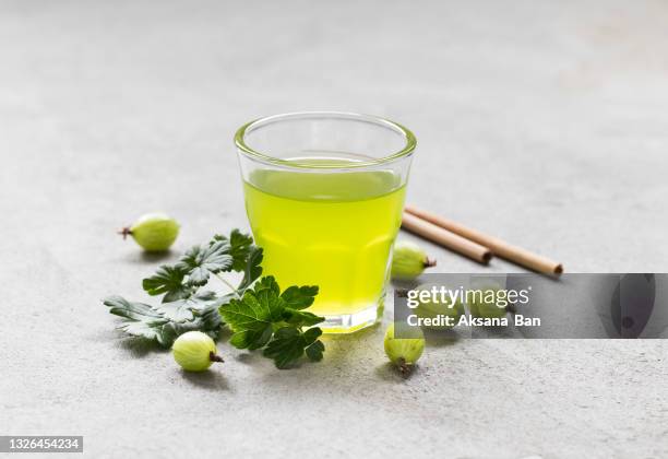 refreshing gooseberry drink cocktail in a glass with bamboo straw on a light gray background - stachelbeere stock-fotos und bilder