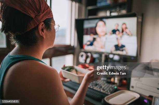 asian chinese mid adult woman videocall in front of desktop pc monitor screen together with family friends during dinner time - virtual lunch stock pictures, royalty-free photos & images