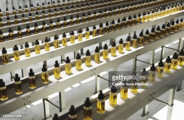 botellas de aceite de cbd en una línea de producción - cannabis oil fotografías e imágenes de stock
