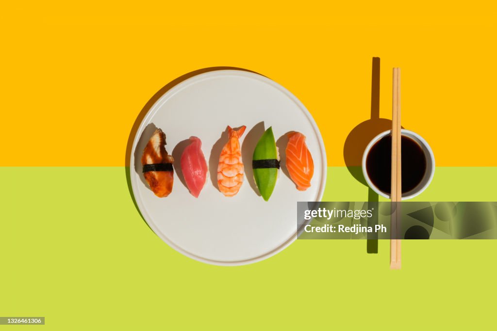 Food photo sushi with shrimp, avocado, salmon, tuna, eel on plate in trendy color block style. Top view. Flat lay.
