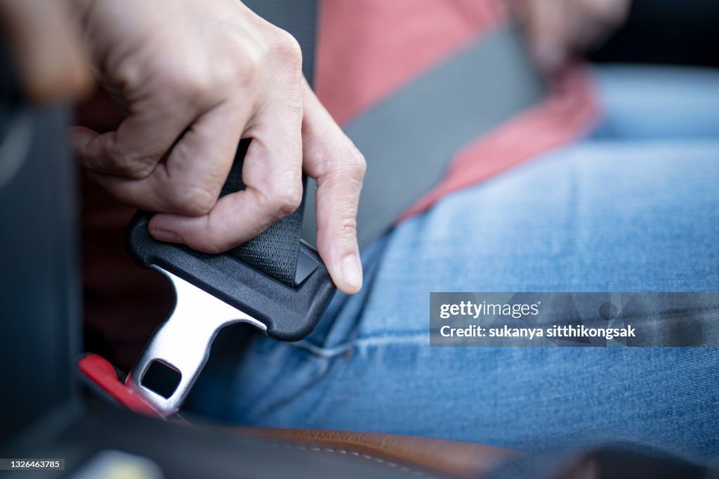 Car safety concept; Close up of hand woman pulling seat belt in her car.
