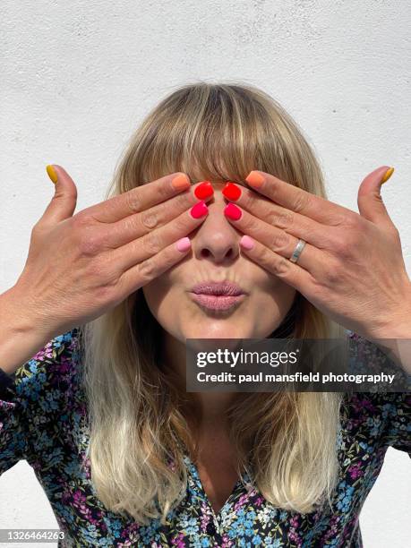 lady covering eyes with fingers whilst pouting - paul mansfield photography fotografías e imágenes de stock