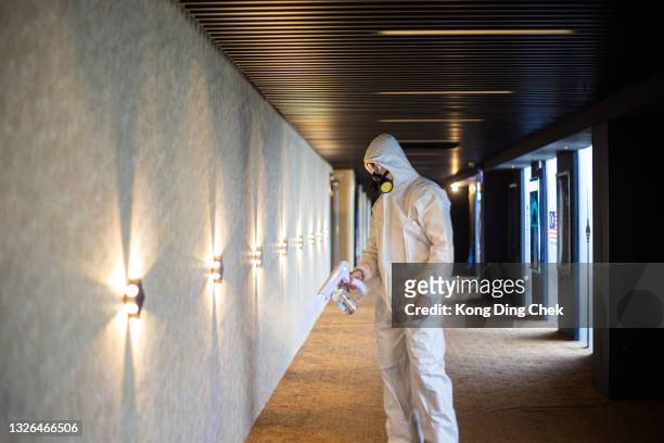 asian chinese cinema hygienist worker wearing respirator mask performing disinfection in cinema corridor - spray bottle stock pictures, royalty-free photos & images