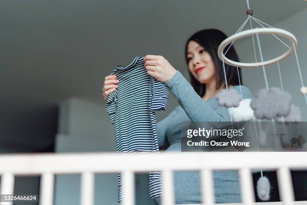 asian pregnant woman getting ready for her newborn baby - modern baby nursery stock pictures, royalty-free photos & images