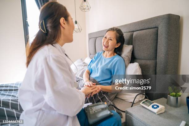 若いアジアの女性医師は、自宅で成熟した女性の血圧をチェック - high blood pressure ストックフォトと画像