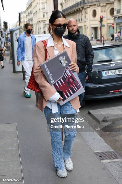 Bella Hadid comes out of a store with a Backgammon game set in her arms on July 01, 2021 in Paris, France.