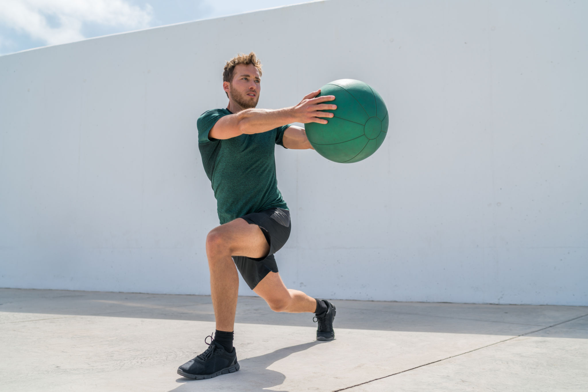 Working out man training legs and core ab workout doing lunge twist exercise with medicine ball weight. Gym athlete doing lunges and torso rotations for abs training. Working out man training legs and core ab workout doing lunge twist exercise with medicine ball weight. Gym athlete doing lunges and torso rotations for abs training.