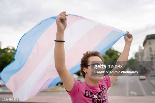 man holding transgender flag in the air - non binary stereotypes stock pictures, royalty-free photos & images