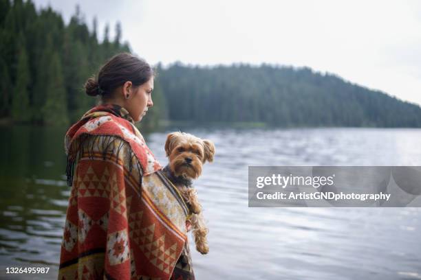 woman holding dog around mountain lake. - yorkshire terrier stock pictures, royalty-free photos & images