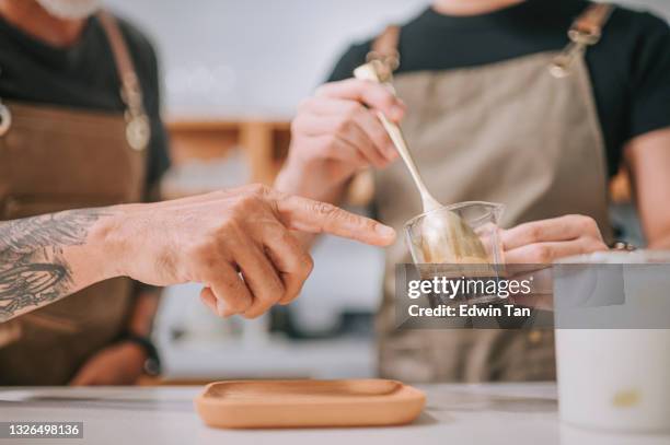 close up hands of asian chinese senior male barista teaching his daughter making coffee at cafe bar counter - coaster stock pictures, royalty-free photos & images