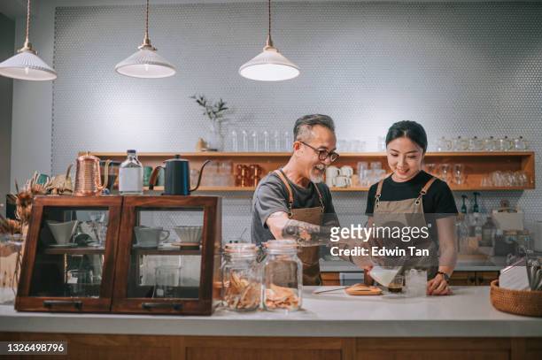 asiatische chinesische senior männlichen barista lehrt seine tochter kaffee in café-bar-theke - small business people working in asia stock-fotos und bilder