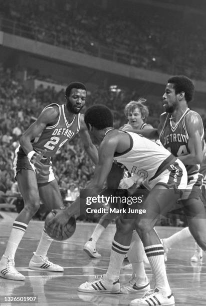 Denver Nuggets guard Jim Price holds the ball away from Detroit Pistons forward Marvin Barnes and guard Eric Money during an NBA basketball game...