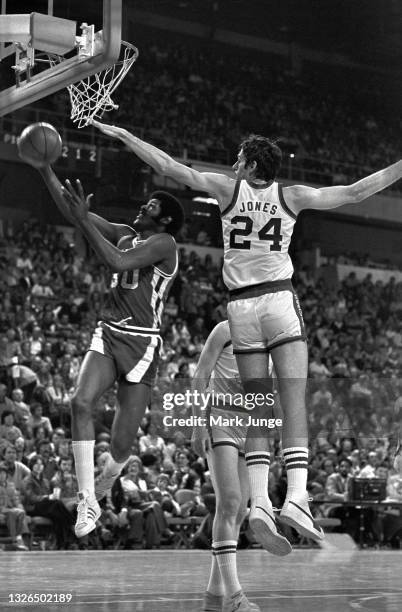 Detroit Pistons forward M.L. Carr drives for a layup under the arms of Denver Nuggets forward Bobby Jones during an NBA basketball game at McNichols...