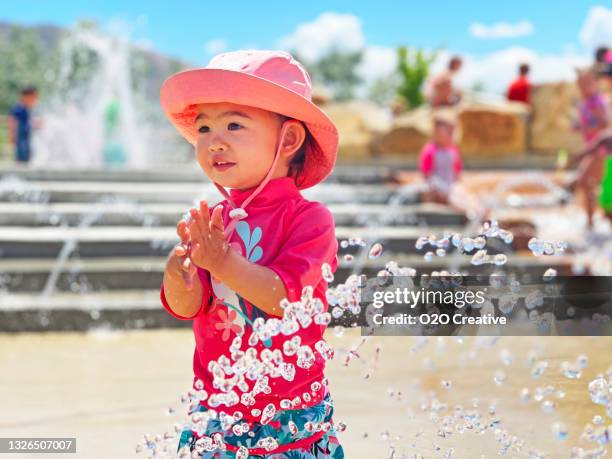 little girl playing at a splashpad - baby at splash pad stock pictures, royalty-free photos & images
