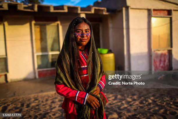 Young indigenous woman with her face painted in a traditional way poses in front of her house at sunset in the town of Punta Chueca during a...