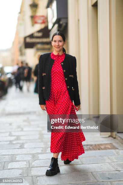 Clara Cornet wears a red midi dress with printed polka dots, a black tweed military jacket with golden buttons, black leather shoes, during the...