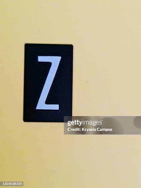 a white colored capital letter z on a black plate over a yellow backdrop - buchstabe z stock-fotos und bilder