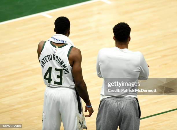 Thanasis Antetokounmpo and brother Giannis Antetokounmpo of the Milwaukee Bucks look on from the sidelines against the Atlanta Hawksduring the second...