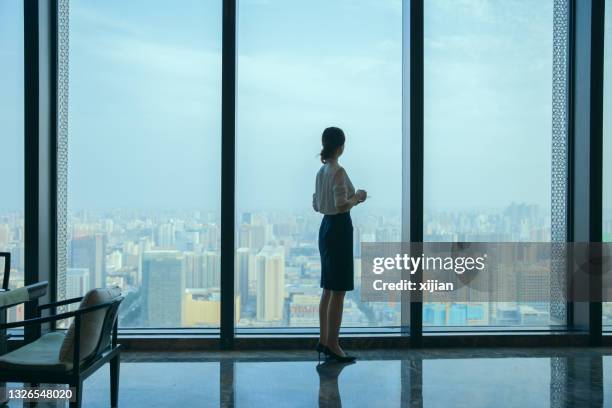 businesswoman looking at city skyline through office window - asia skyline stock pictures, royalty-free photos & images