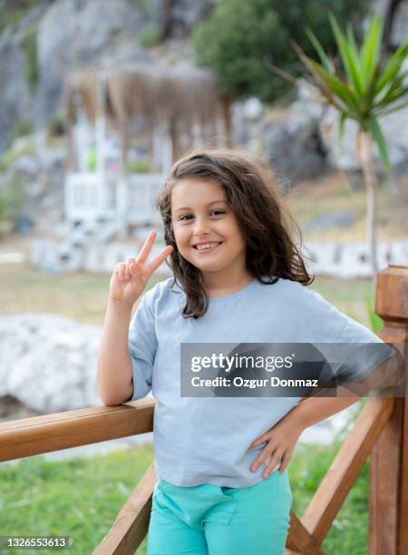 cute little girl with a beautiful smile posing at backyard - victory sign smile foto e immagini stock