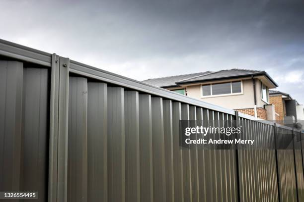 metal  boundary fence, house rooftops in suburb, neighbours - new housing development sign stock pictures, royalty-free photos & images