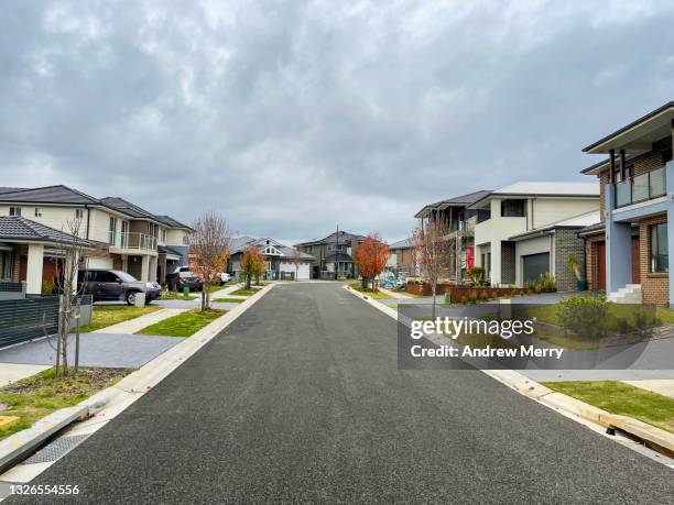 houses along suburban street and overcast sky - quartier résidentiel photos et images de collection