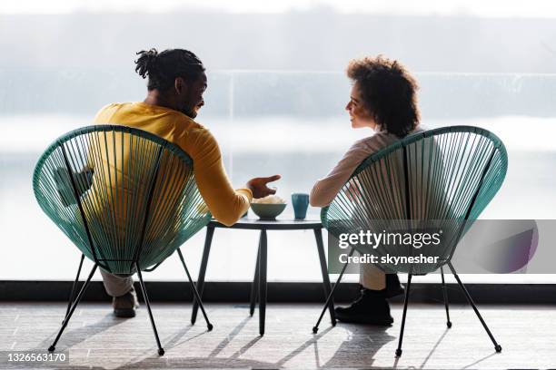 vista trasera de la feliz pareja negra hablando mientras se relaja en una terraza. - té terraza fotografías e imágenes de stock