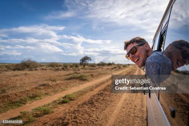 young tourist shows his joy of exploitation in amboseli national park, kenya. africa. - motion sickness stock pictures, royalty-free photos & images