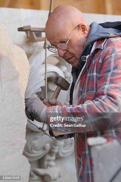 Stone sculptor Carlo Wloch hammers a chisel into sandstone as he copies a gabel decoration in plaster behind him at the Schlossbauhuette studio,...